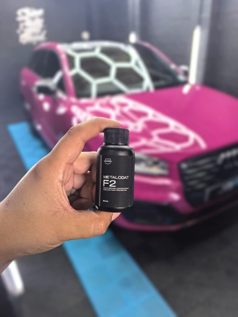Ceramic coating bottle held in front of a pink Audi SUV at AutoHub