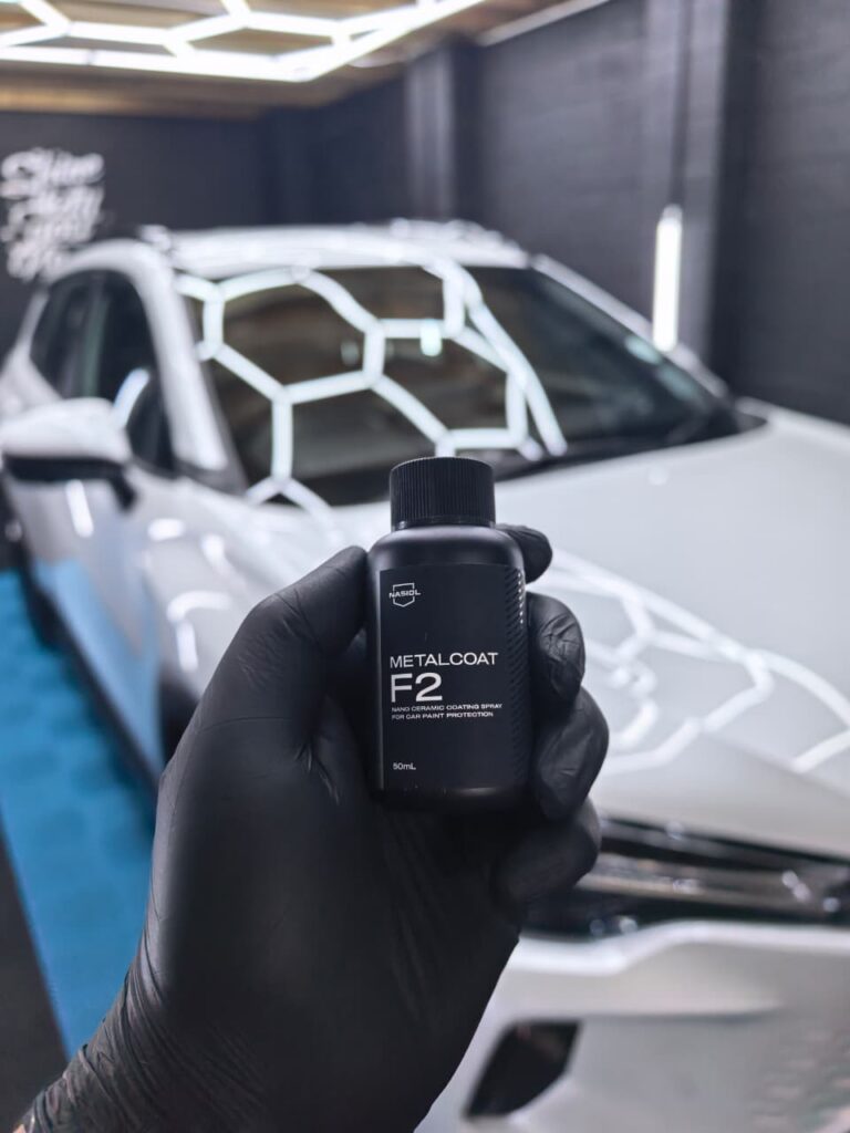 Ceramic coating product held in front of a white Toyota SUV at AutoHub